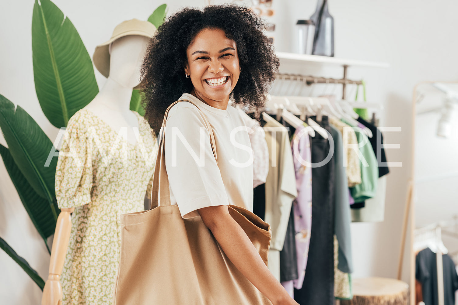 Happy woman with shopping bag looking at camera. Cheerful female standing in a clothing store.