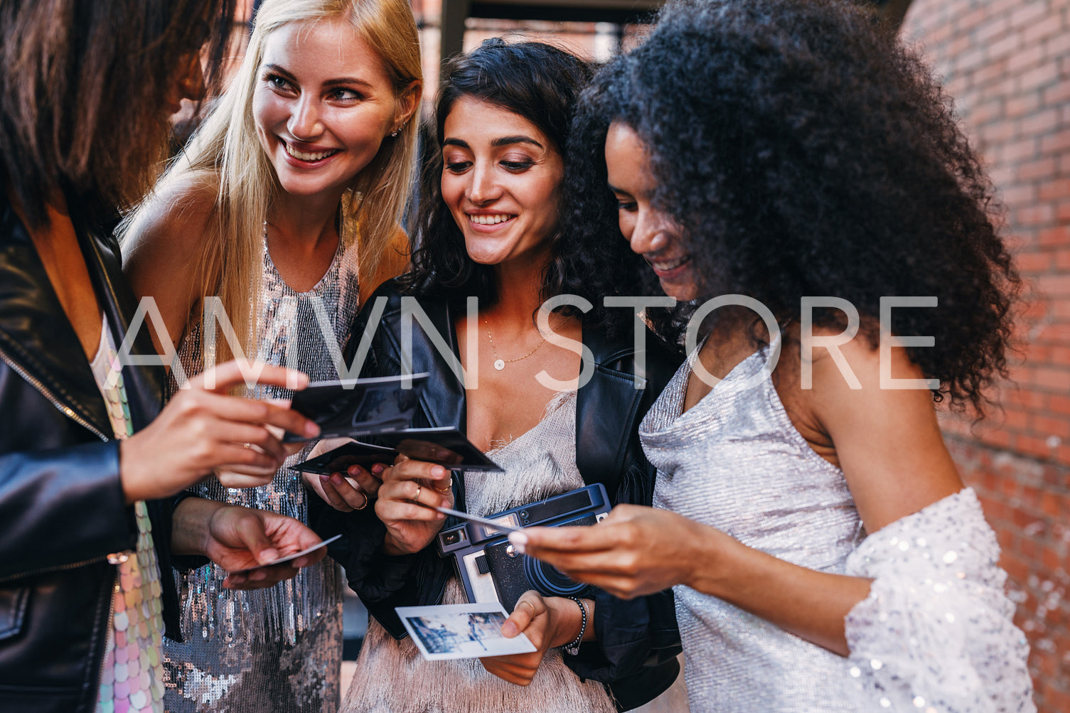 Smiling female friends holding instant photographs outdoors	