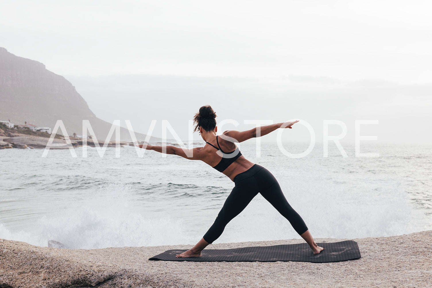 Back view of fit woman doing warming up exercises on mat by ocean