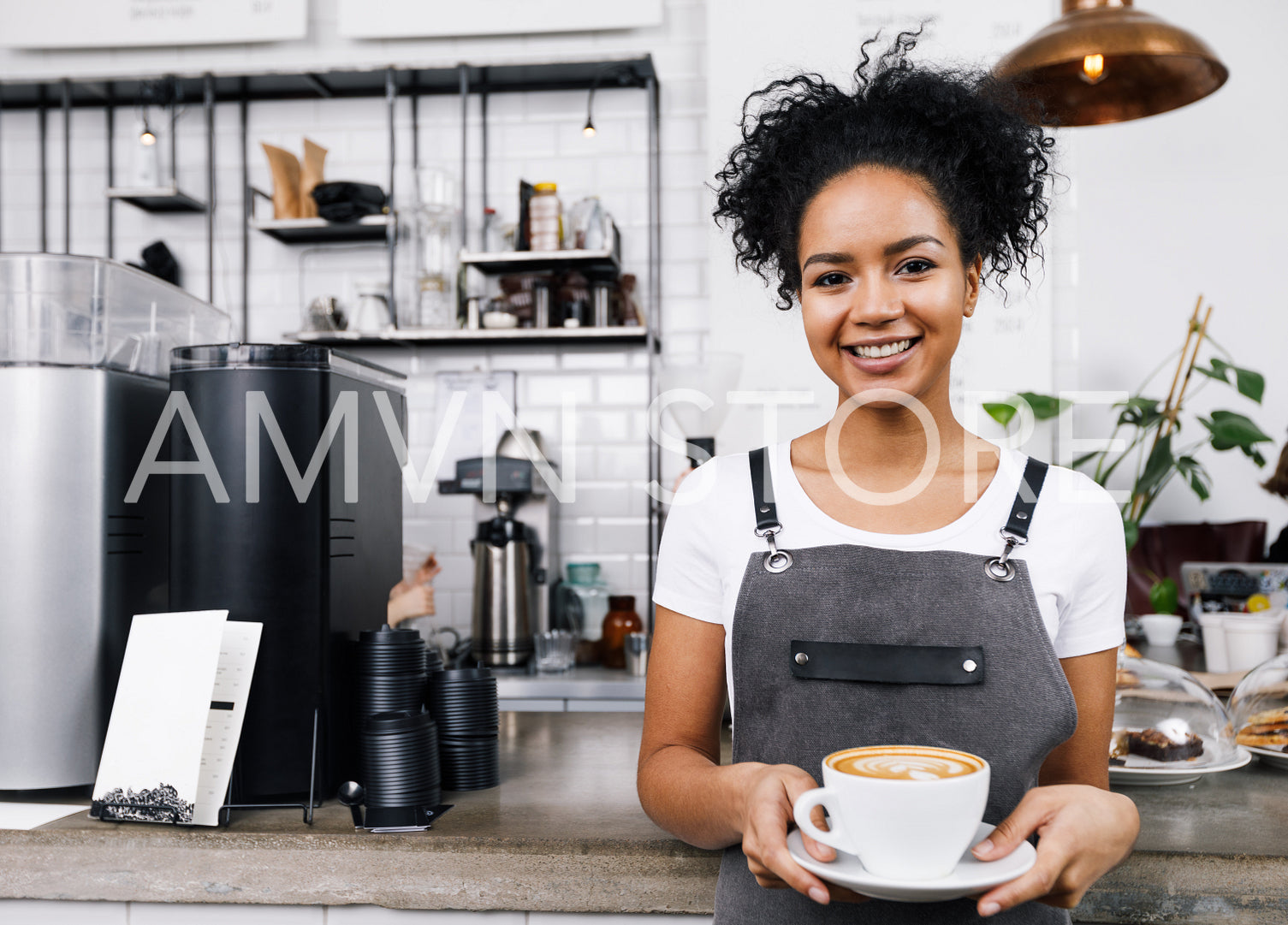 Young smiling woman standing in cafeteria with cup of latte	