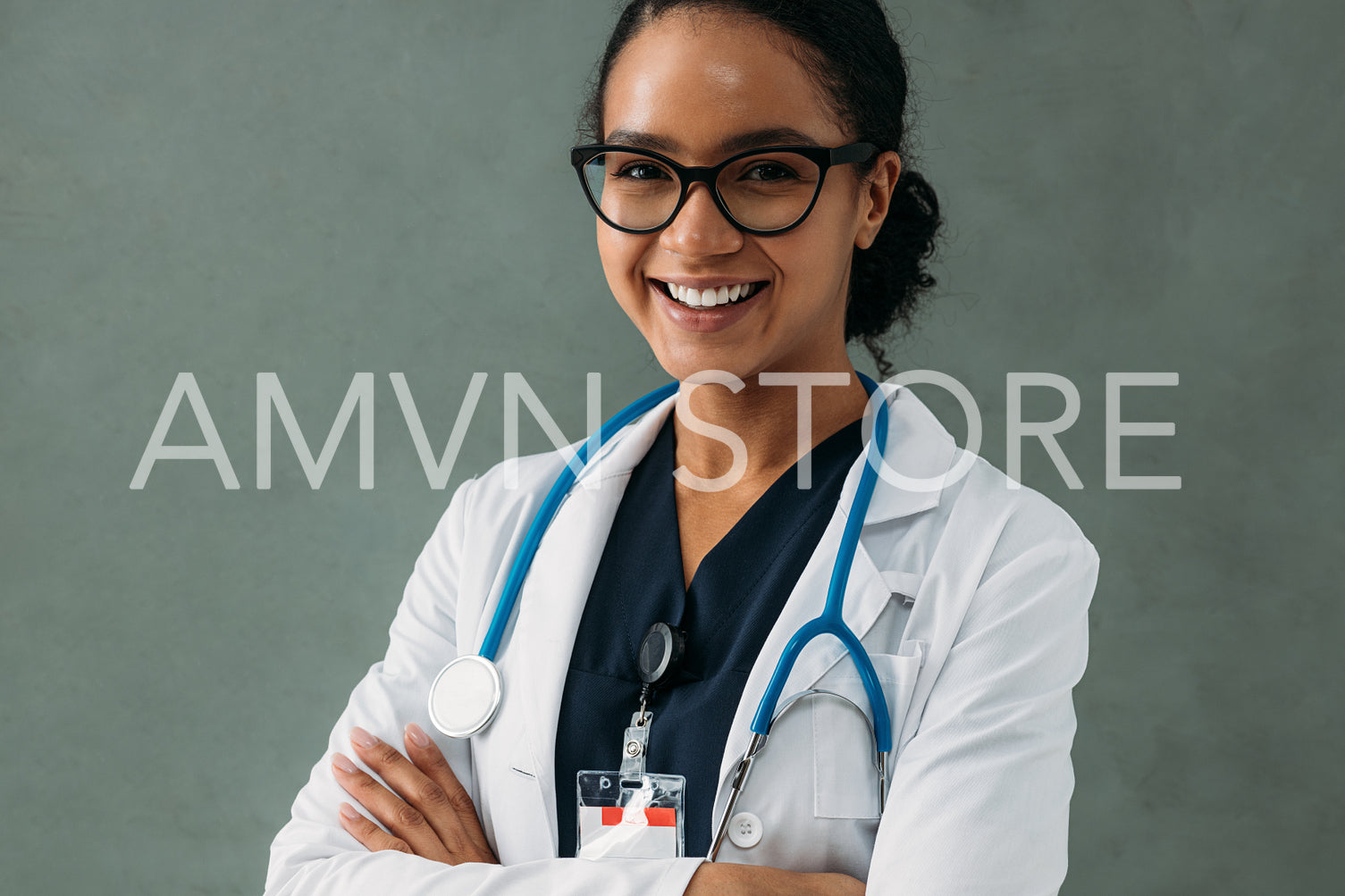 Portrait of a happy doctor in a white lab coat standing with crossed arms looking at camera