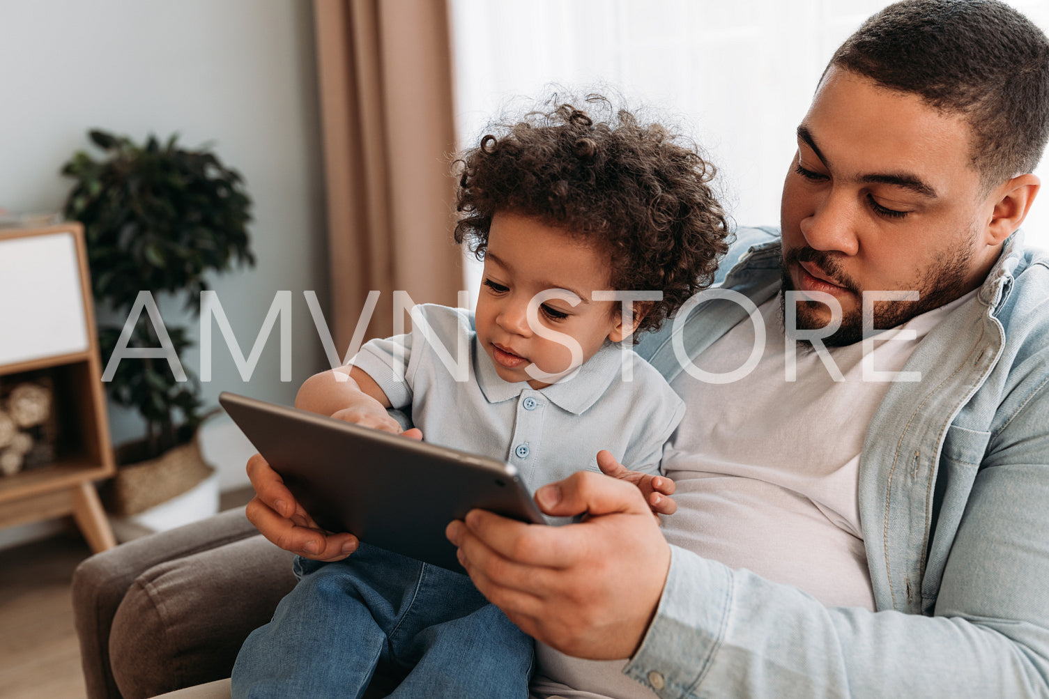 Father and son using digital tablet. Little boy sitting with dad and looking on the tablet.	