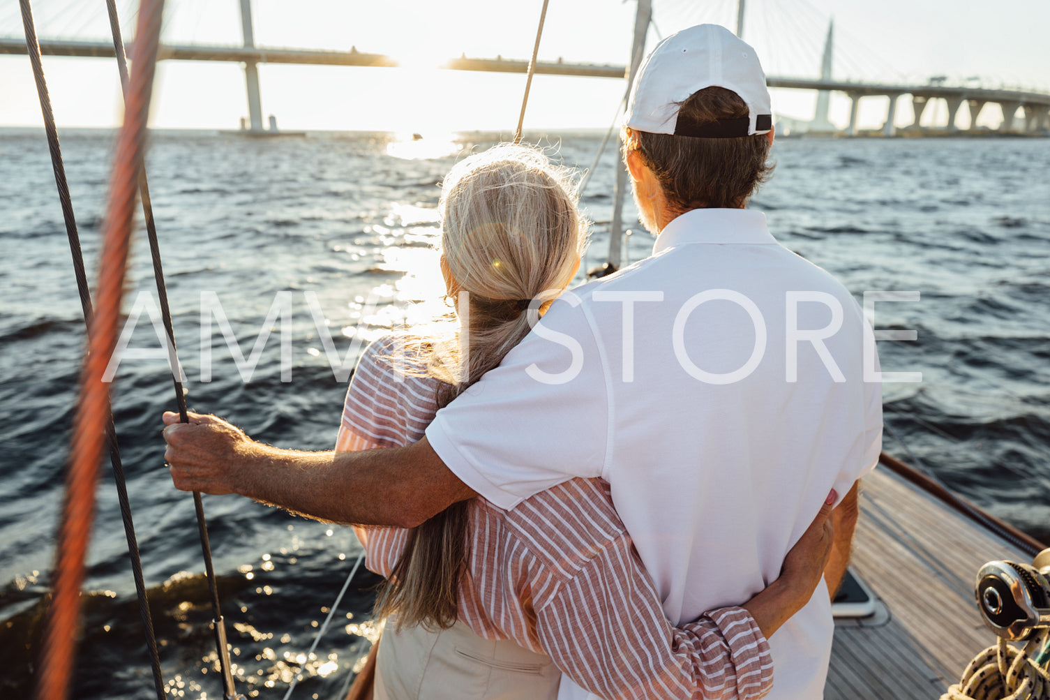 Back view of two mature people hugging together. Senior couple standing on a yacht bow and looking into distance.	