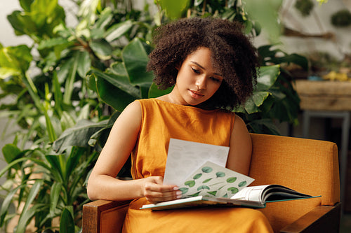 Woman botanist working at her indoor garden sitting on an armchair