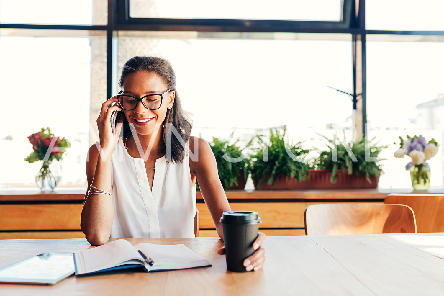 Happy businesswoman talking on smartphone. Female entrepreneur in cafe.	