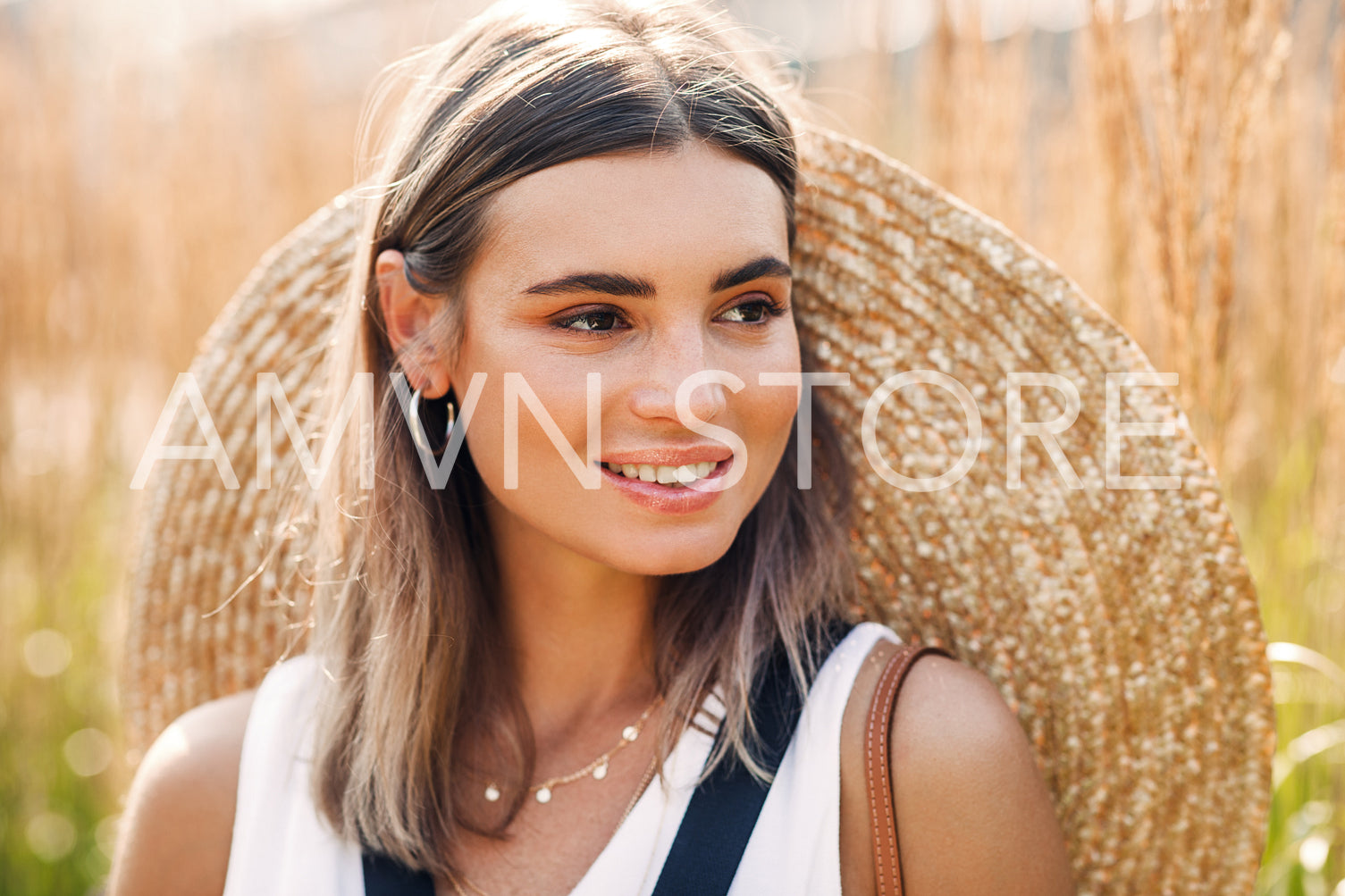 Beautiful blond woman with straw hat on her back looking away	