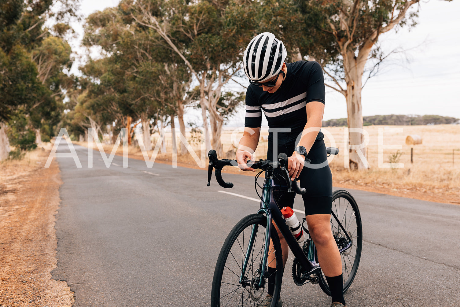 Cyclist woman in sportswear checking on board computer on her road bike during training