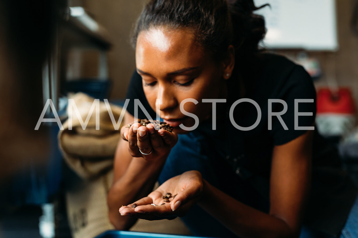 Woman examining and smelling the aroma of coffee beans after roasting	