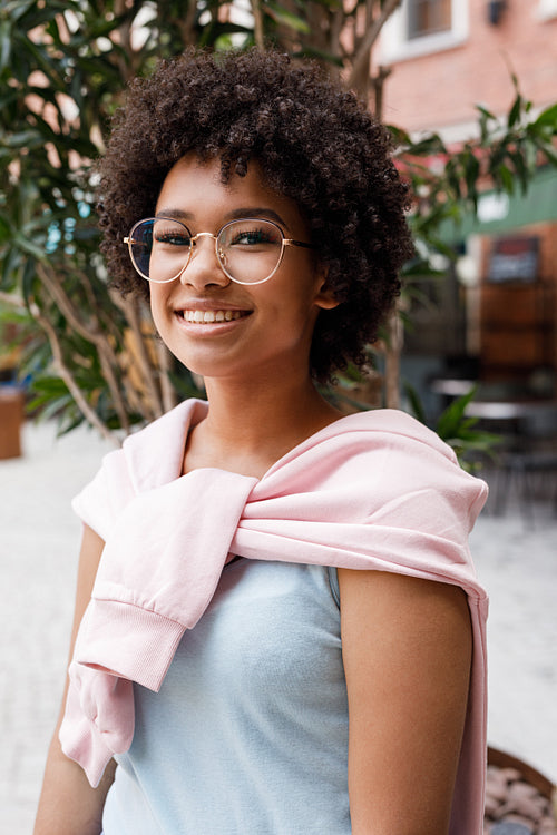 Smiling woman wearing eyeglasses, posing at outdoor cafe