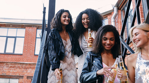 Four female friends walking with bottles of beer