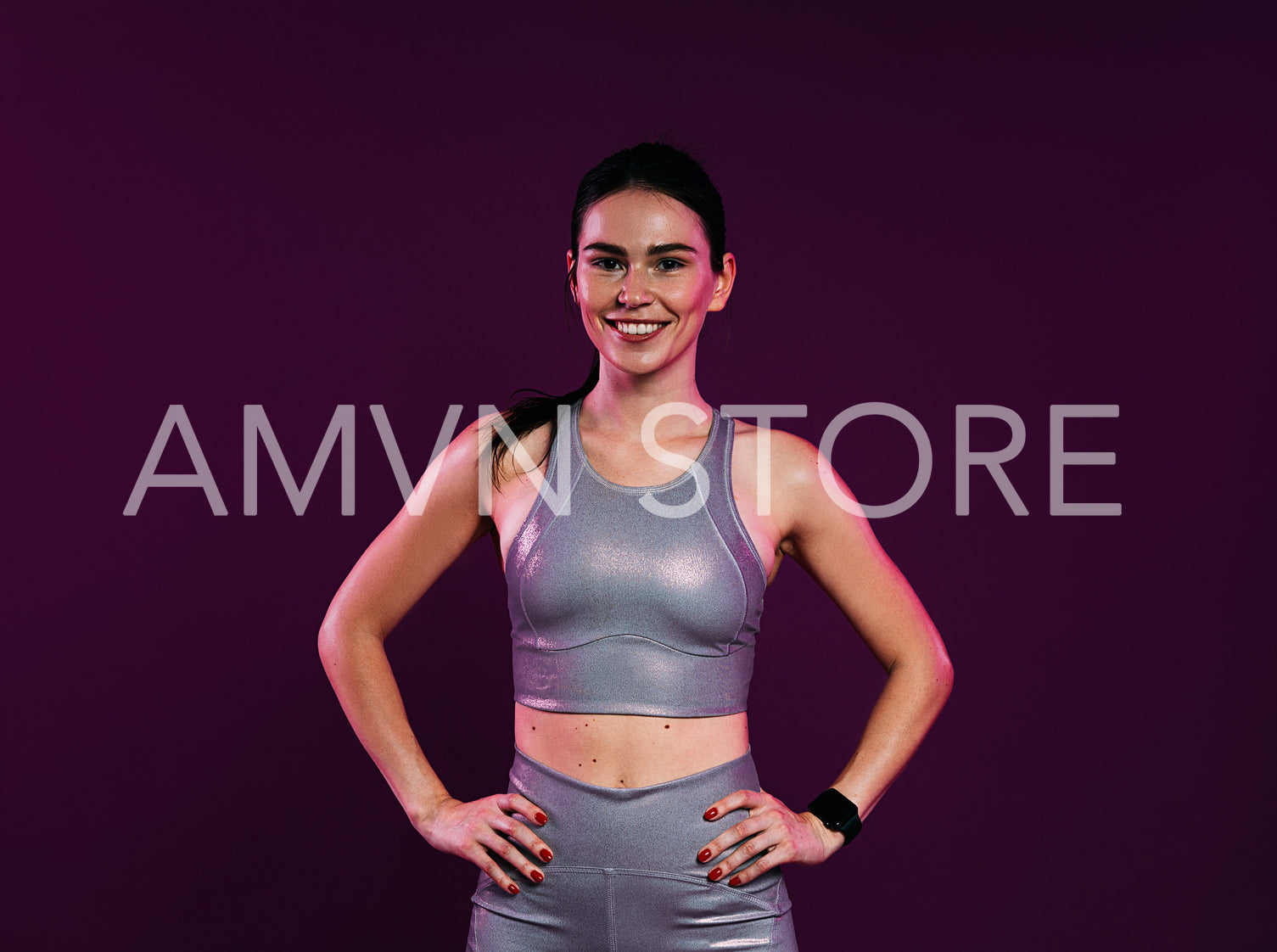 Confident woman in silver fitness attire at magenta backdrop