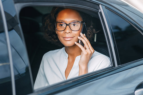 Young woman talking on the cellphone while sitting on back seat of a taxi