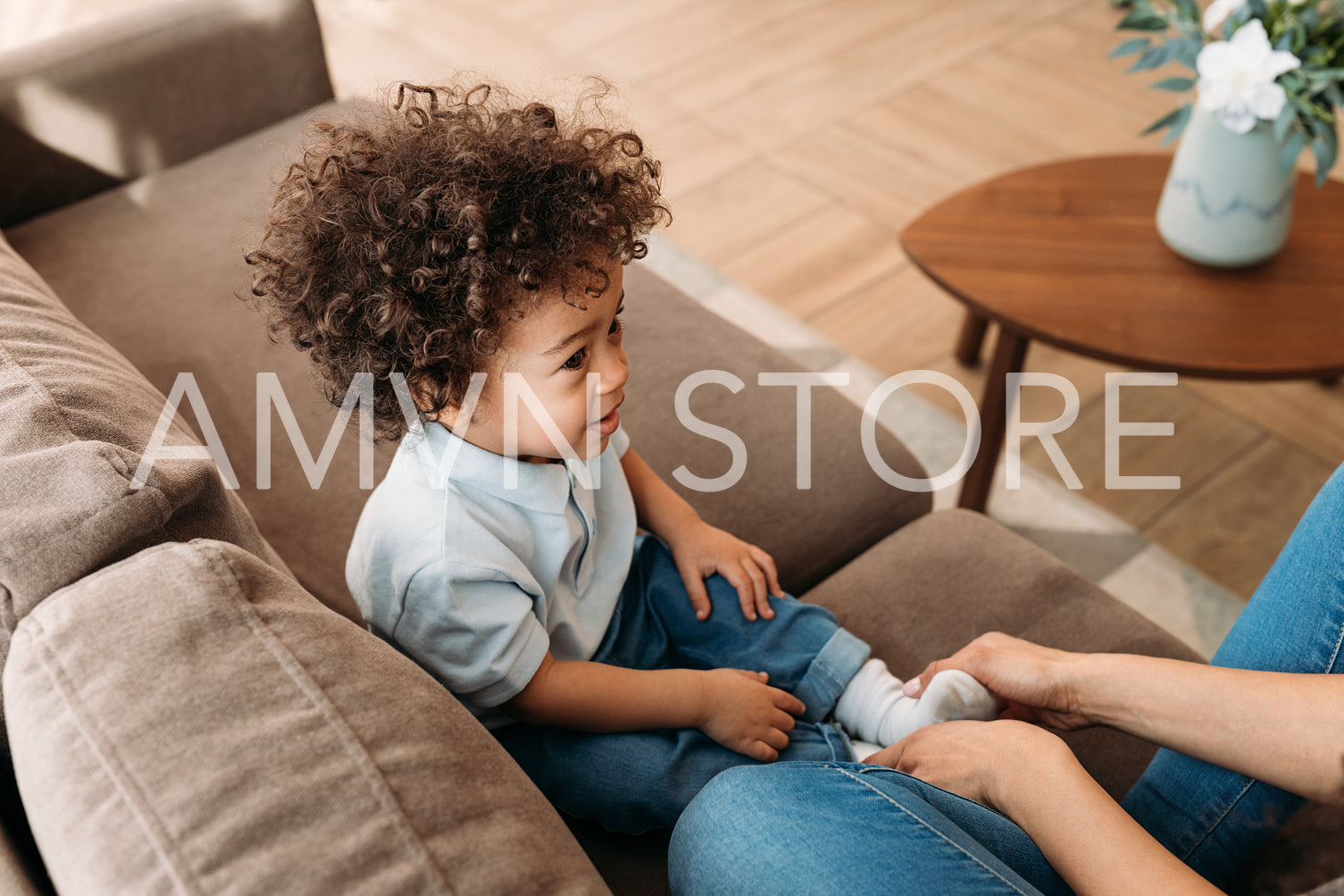 Cute little boy with curly hair sitting on a sofa at home	