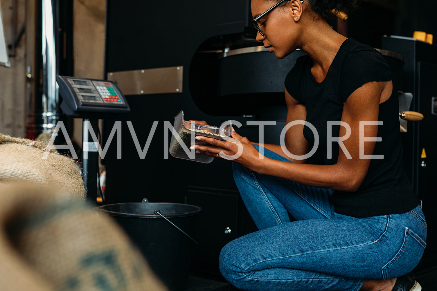 Side view of young barista checking quality of coffee beans before roasting	