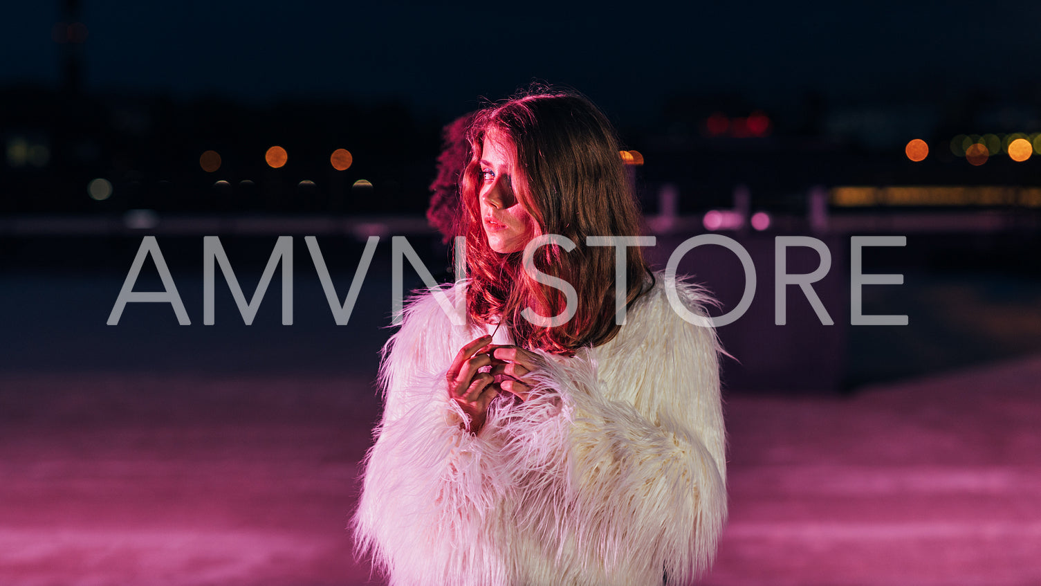 Young blonde woman standing on a roof in front of a pink neon light and looking away	