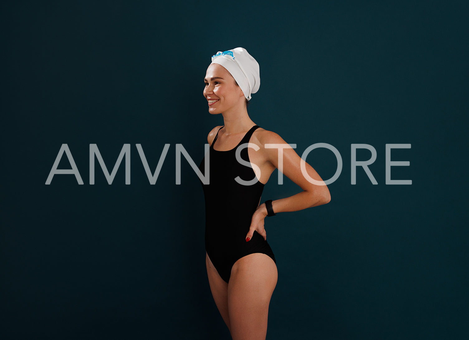 Side view of young smiling female in swimsuit with hands on hips standing over blue backdrop