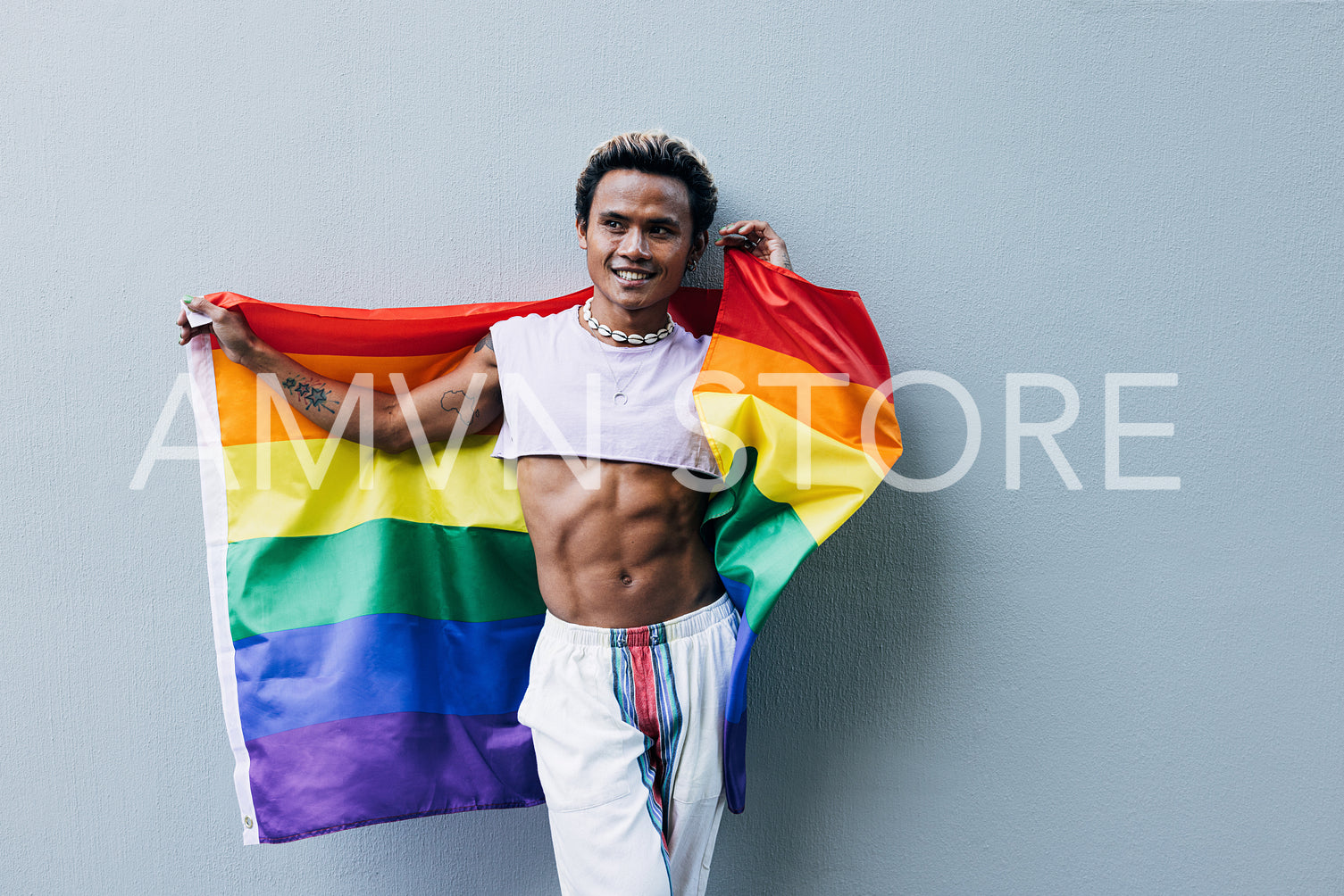 Smiling handsome guy holding rainbow flag outdoors