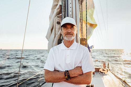 Portrait of a mature confident captain standing on his yacht at mast and looking at camera