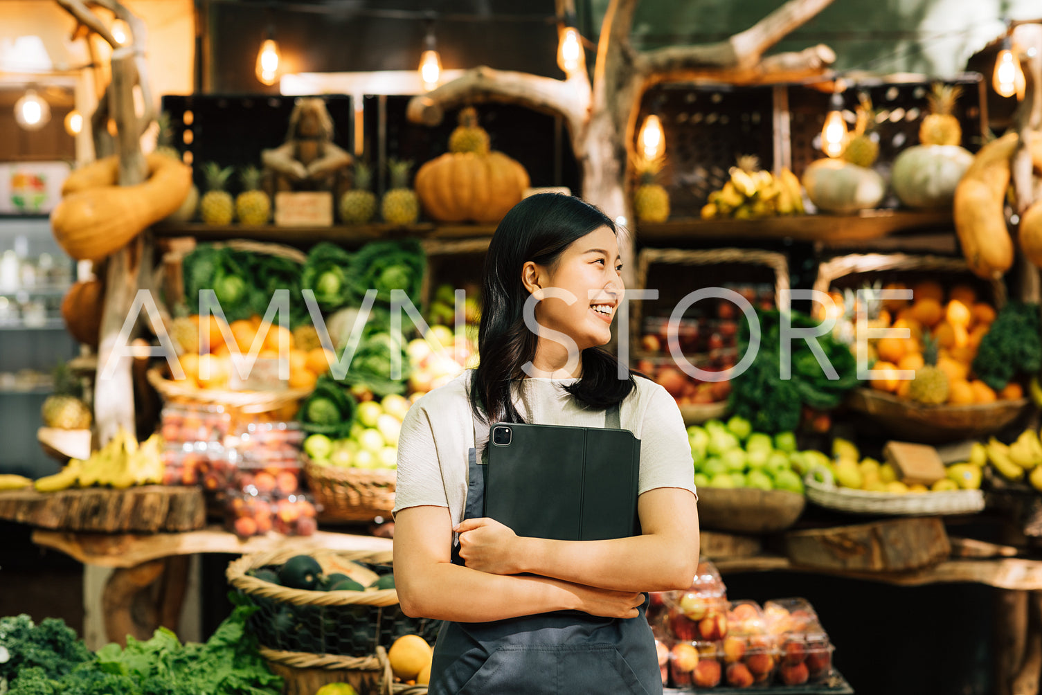 Smiling businesswoman standing at an outdoor market. Female vendor in apron holding digital tablet.