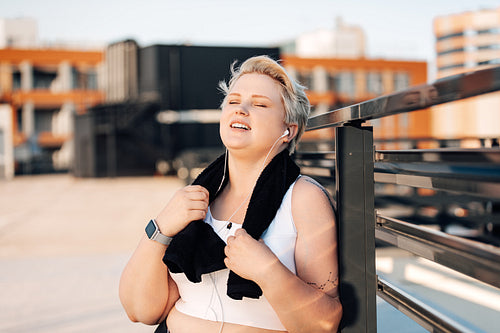 Smiling woman with plus size body holding a towel relaxing after workout