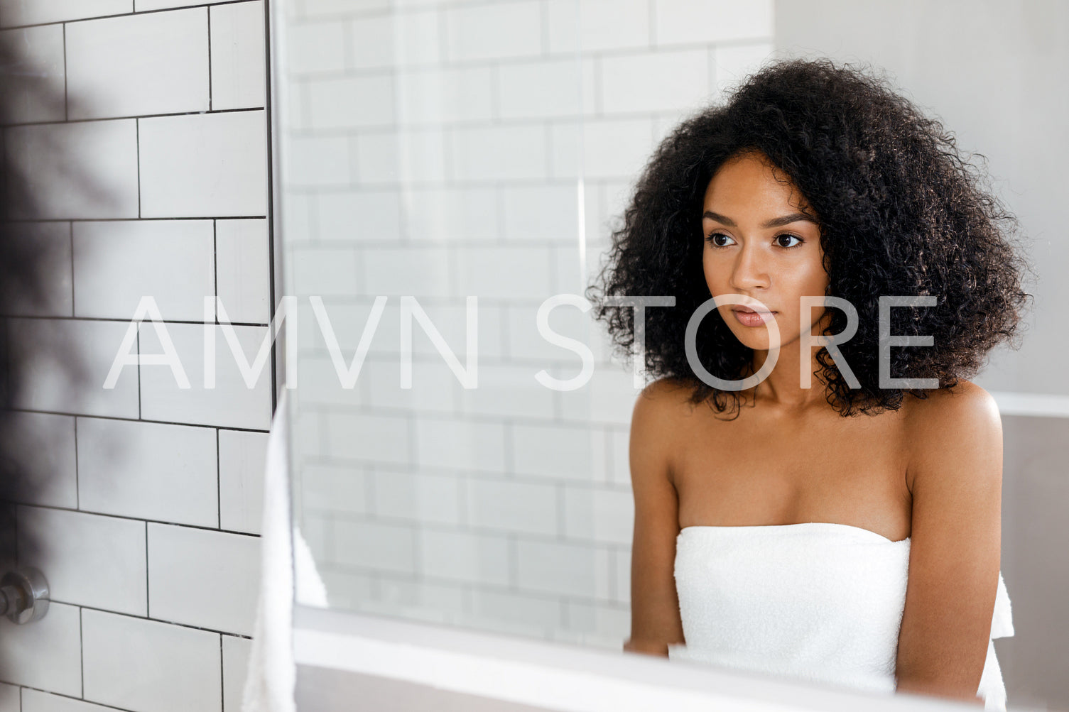 Beautiful woman standing in front of mirror in bathroom with towel around her body	