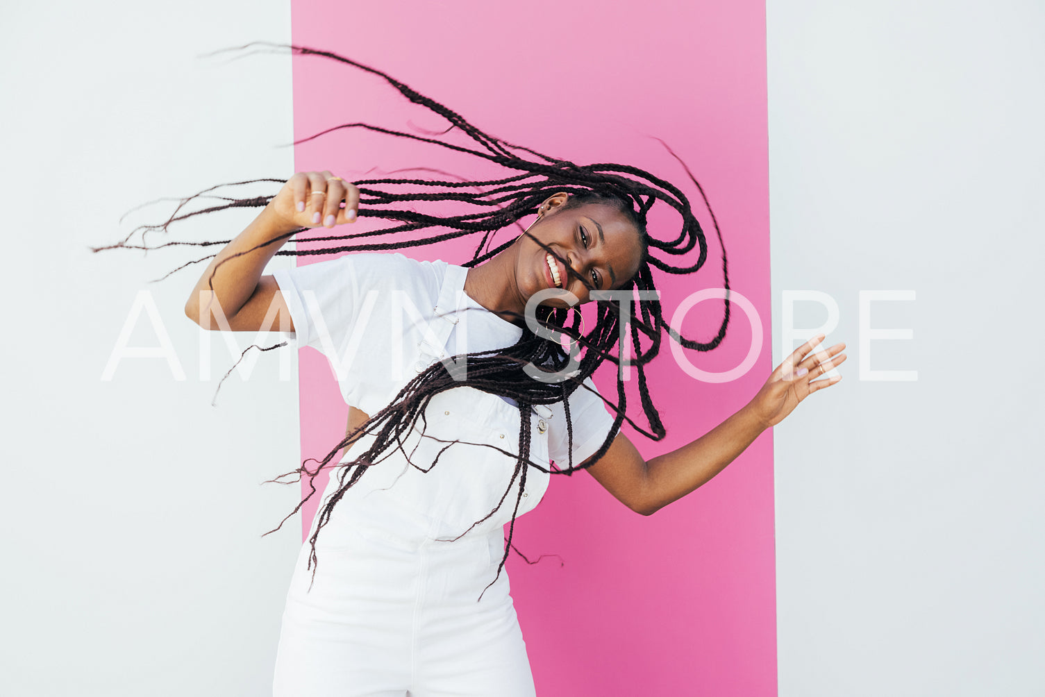 Young happy woman with long hair having fun against white wall with pink stripe