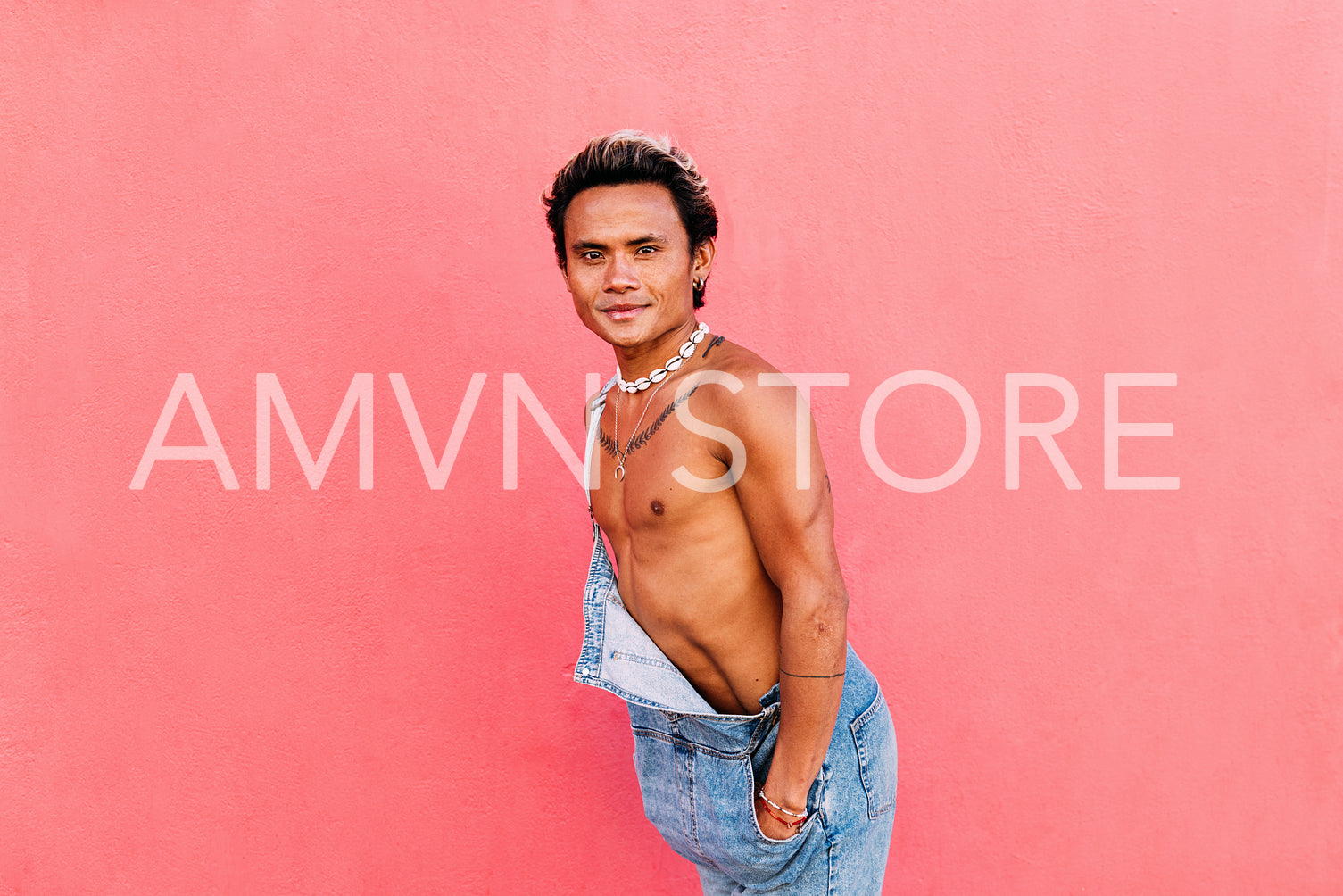 Young handsome guy posing outdoors against pink wall looking at camera