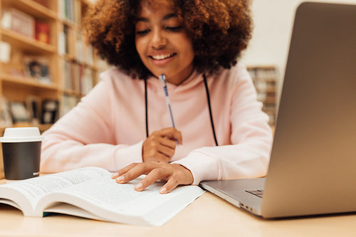 Close up of a girl sitting at desk in library and reading a book