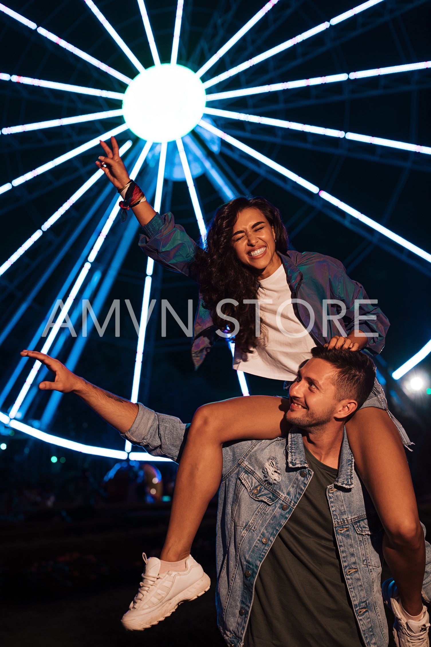 Happy couple having fun at night against lights of ferris wheel