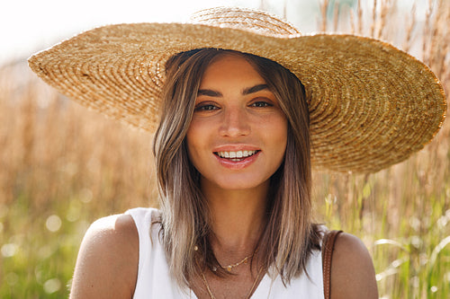 Close up of a Caucasian blond woman in big sun hat looking at camera