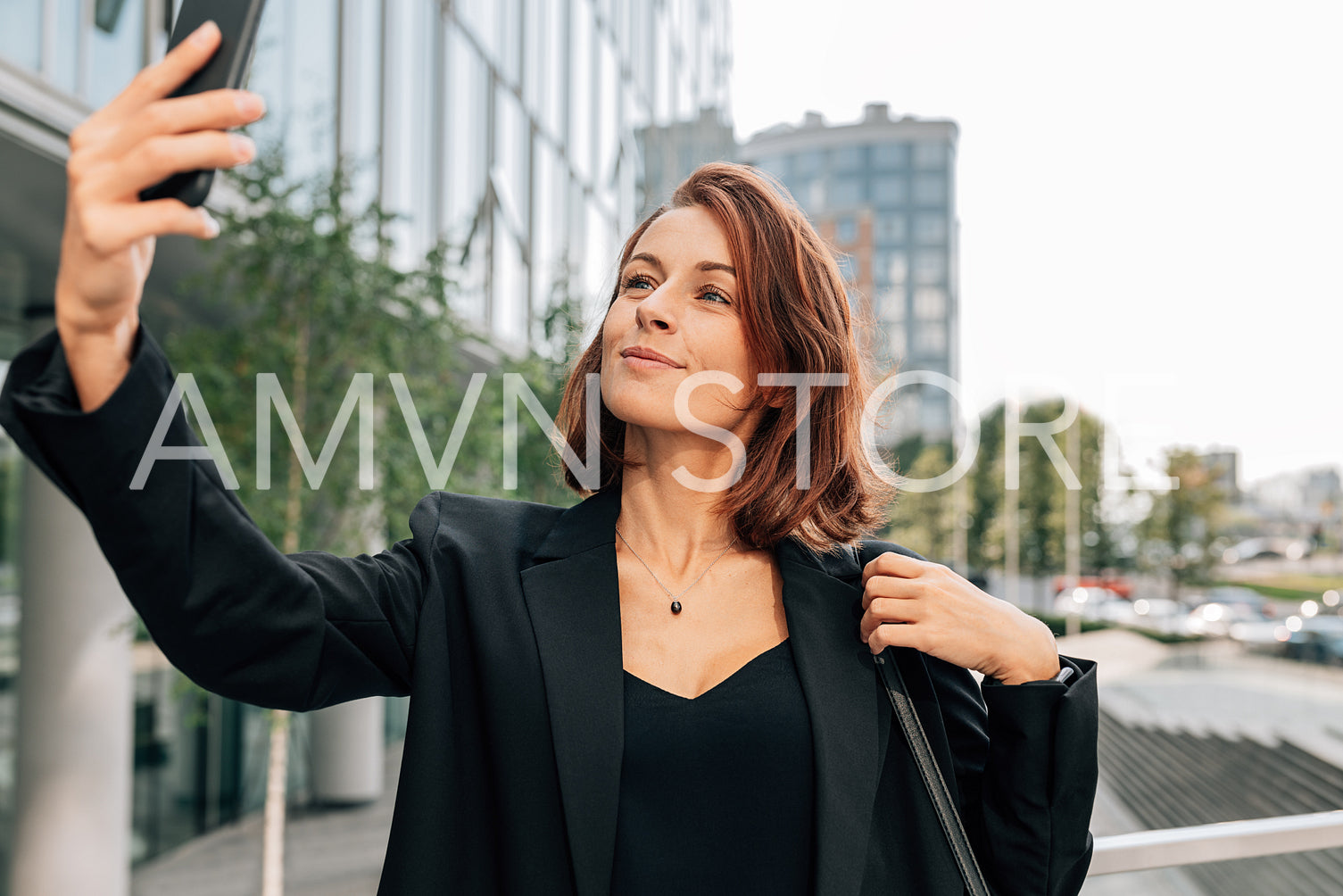 Middle-aged businesswoman with ginger hair taking a selfie while standing outdoors