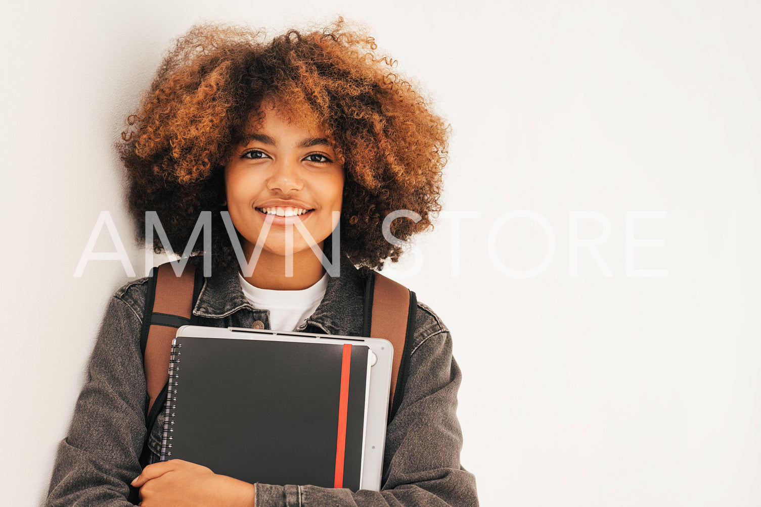 Portrait of a school girl with laptop and notebooks looking at camera