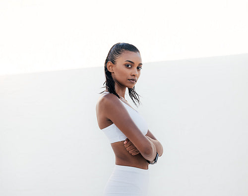 Confident sportswoman in white fitness attire with crossed arms