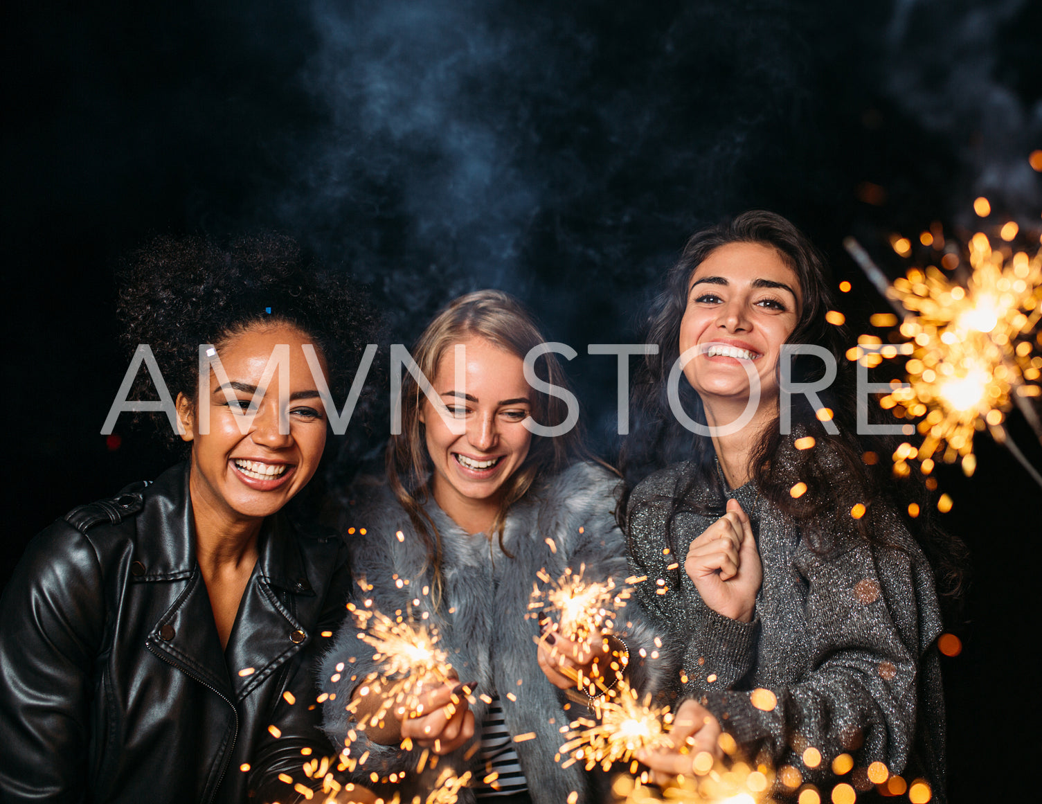 Three young women laughing at night and holding sparklers