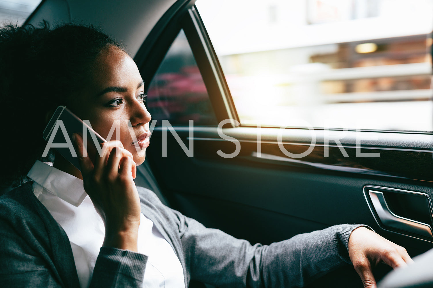 Young businesswoman talking on mobile phone, sitting on back seat of a car	