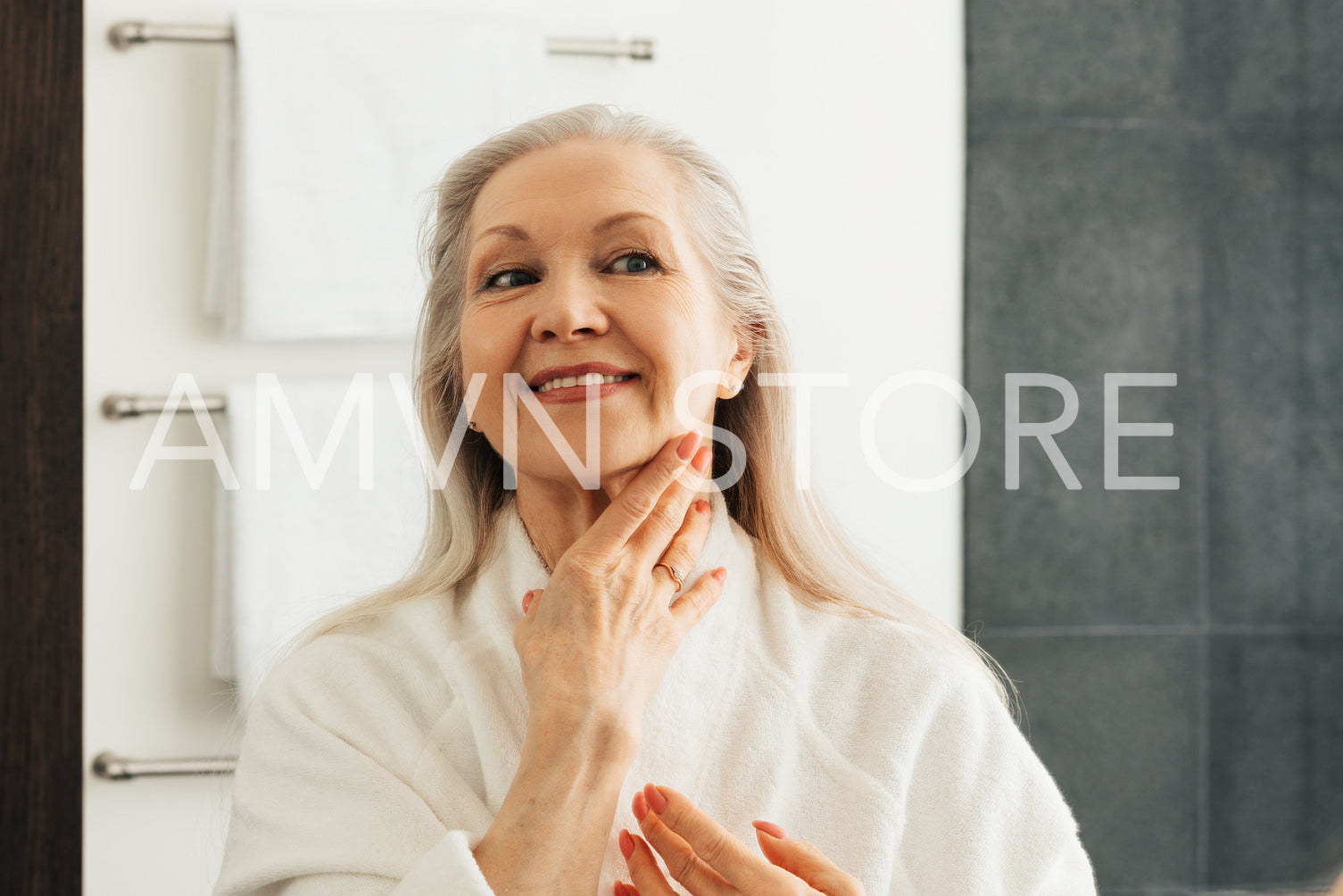 Smiling senior woman touching skin on her neck in front of a mirror