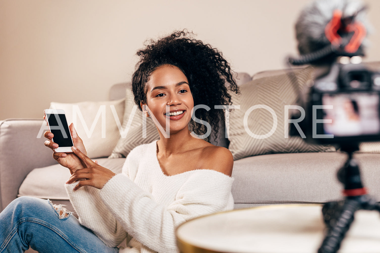 Female vlogger holding smartphone while recording video in living room	