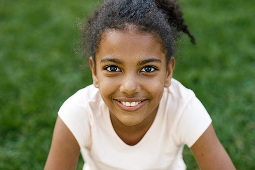 Close up portrait of cute smiling girl, sitting on grass