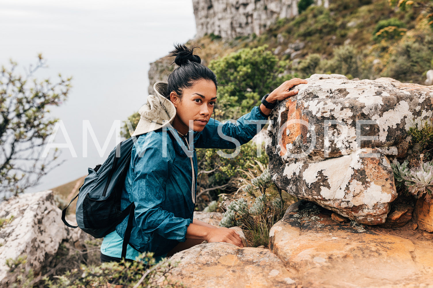 Portrait of woman hiker climbing rock and looking away. Young female hiking mountain.