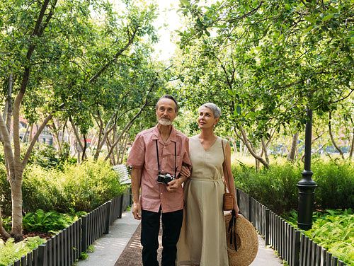 Mature tourists walking in the park. Senior couple walking together in the park during the day.