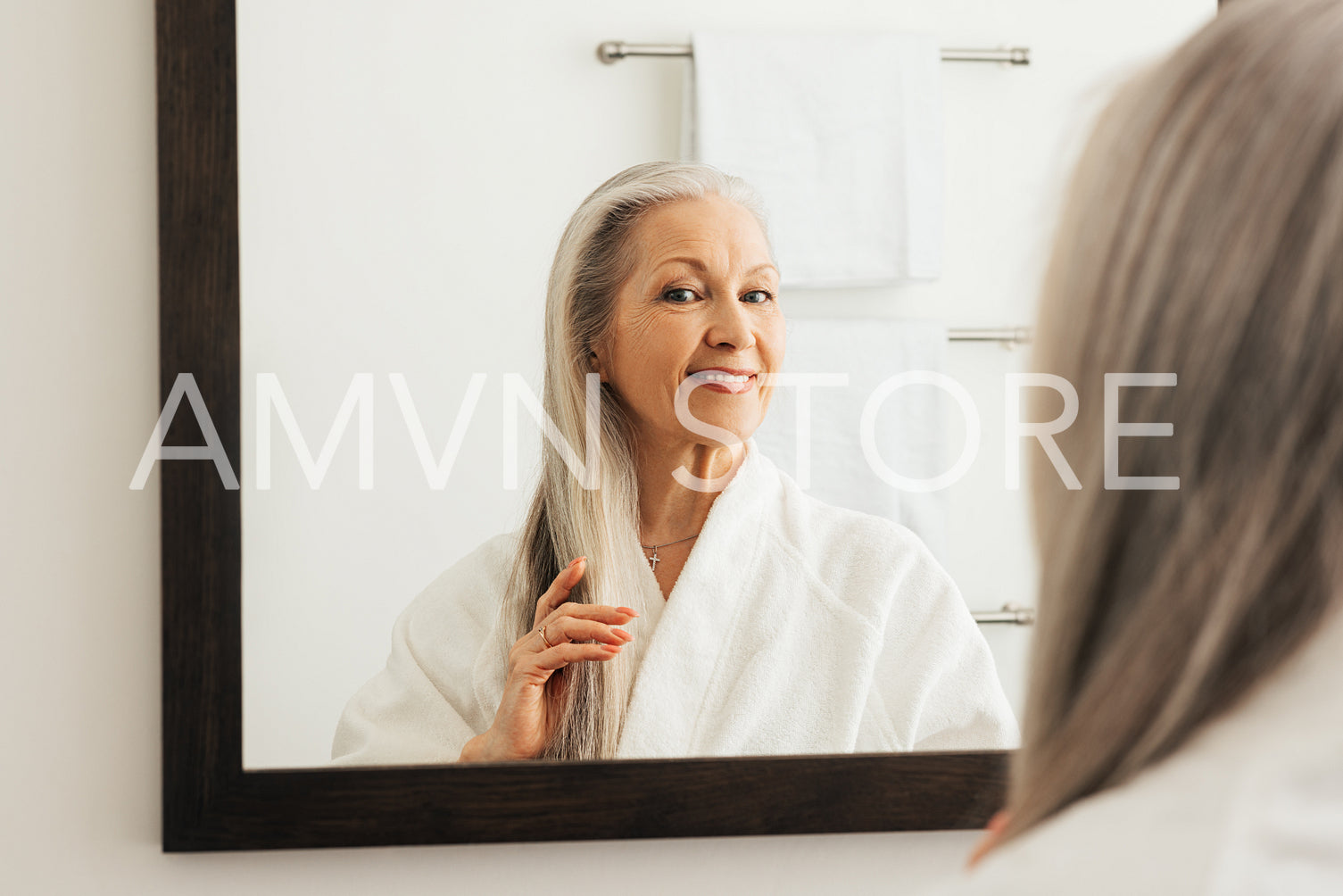 Aged woman admires her long gray hair