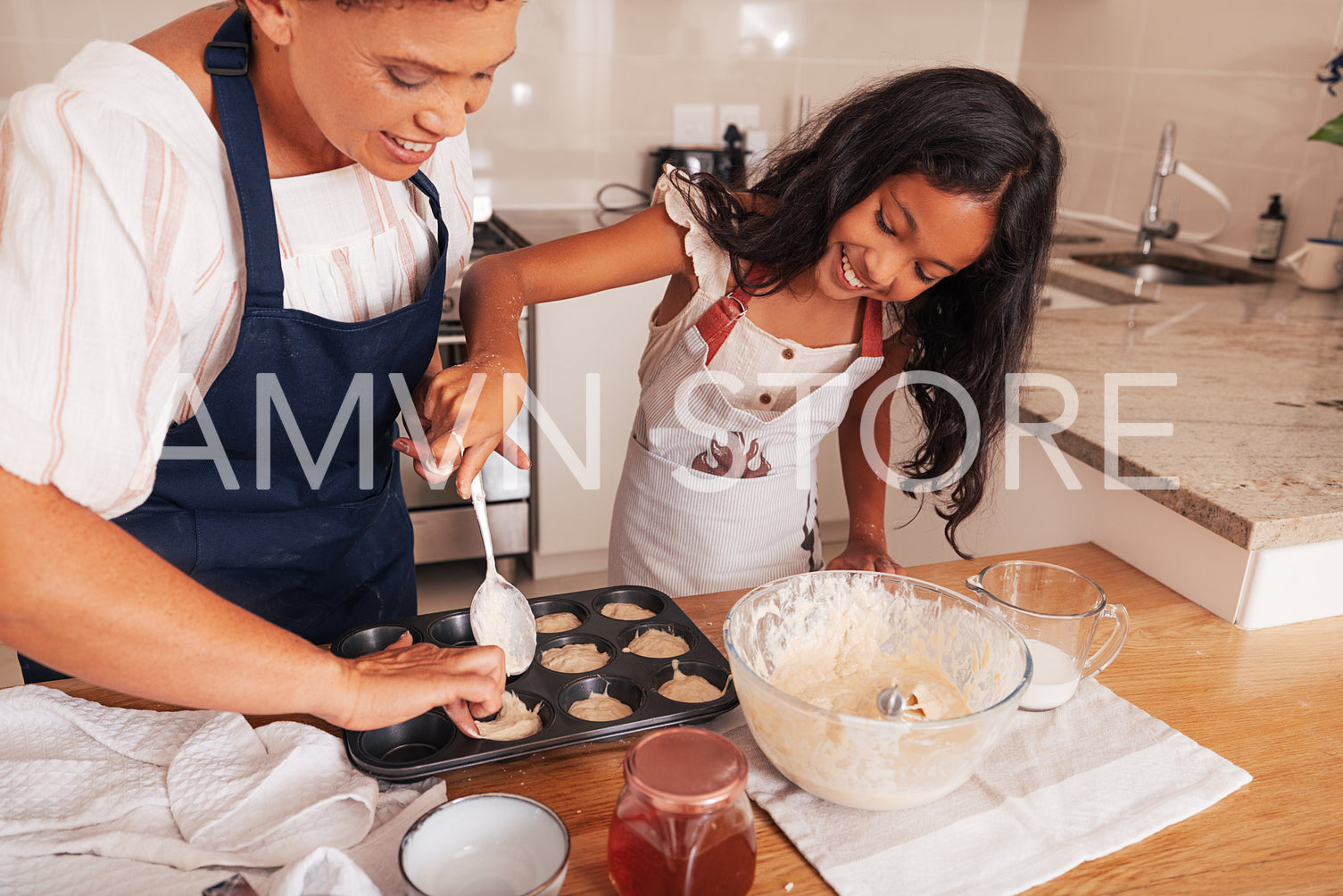 Smiling girl and her grandma making cupcakes in a kitchen