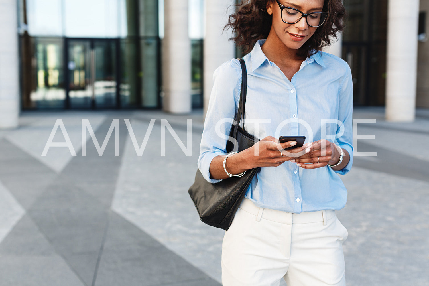 African woman walking outside with smartphone. Female manager typing text message.	