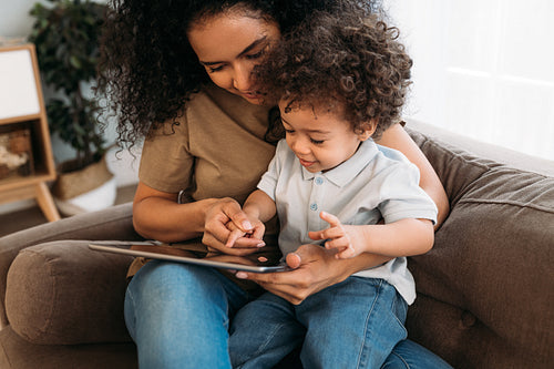 Young mother helping her little son with learning app