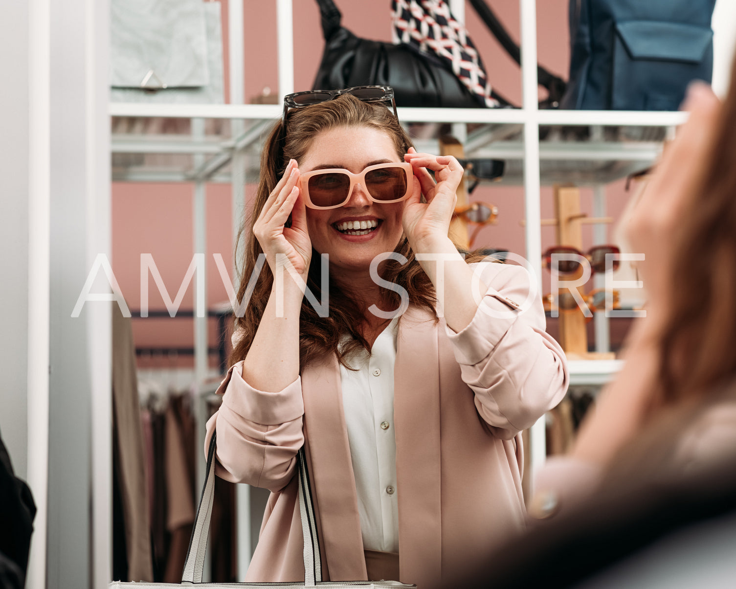 Laughing woman try on sunglasses in front of a mirror in a fashi