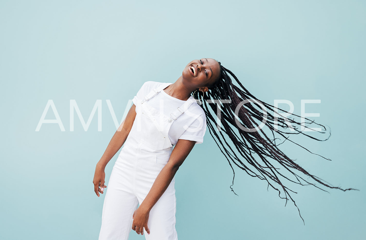 Happy woman with long braided hair having fun against a blue wall outdoors