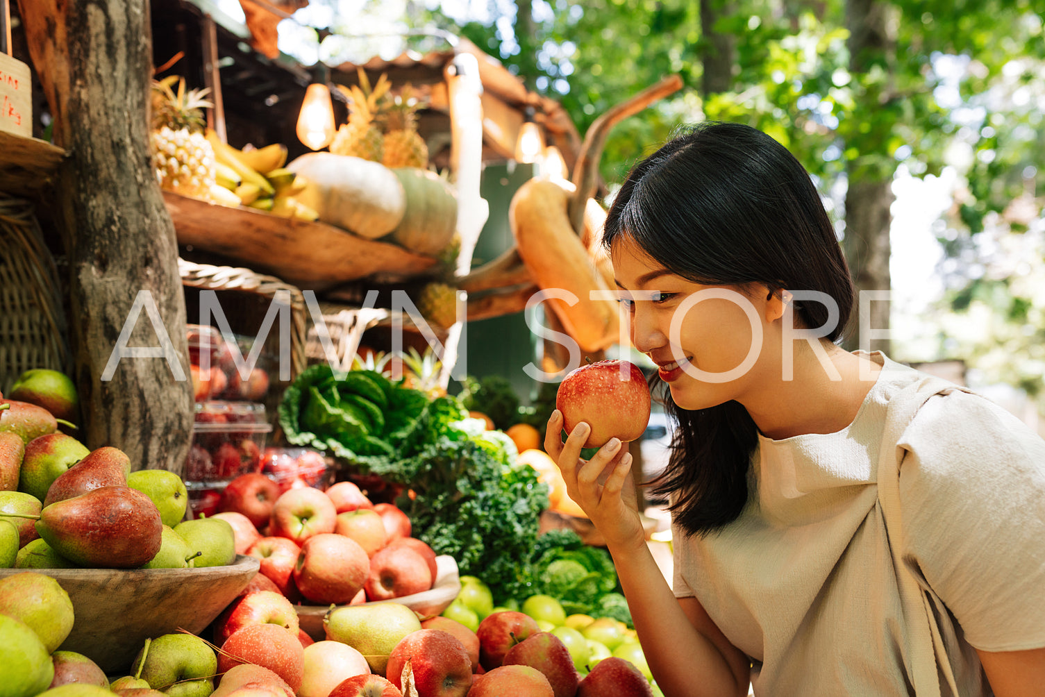 Asian woman smelling an apple at the counter