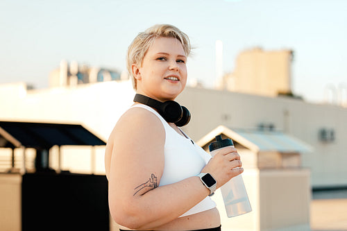 Portrait of a young curvy woman holding a bottle taking a break