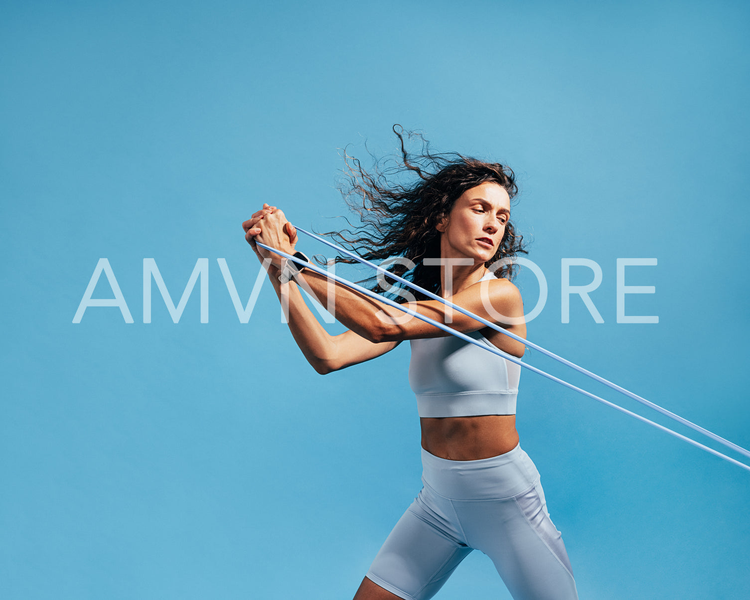 Female athlete working out with stretch bands on blue background. Woman doing intense training using resistance bands.