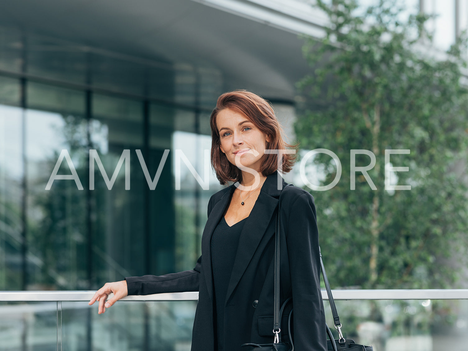 Middle-aged female with ginger hair leaning railing a business building, wearing black formal clothes